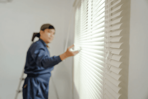 Technician adjusting smart white blinds in a contemporary Dubai home, representing advanced easy-to-install window treatments.