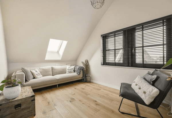 Chic attic living room in Dubai featuring sleek black venetian blinds, modern furniture, and warm wood flooring.