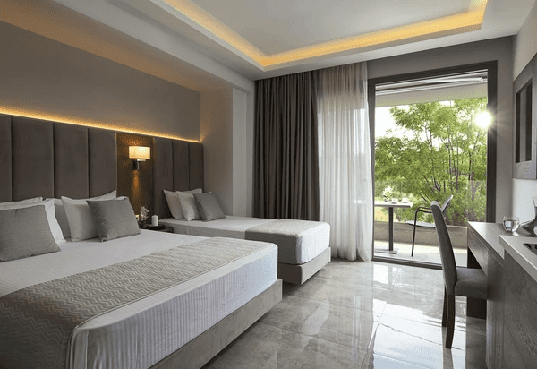 Modern luxury bedroom with hotel-style blackout curtains and sheer layers, overlooking a green outdoor balcony in Dubai 2025.