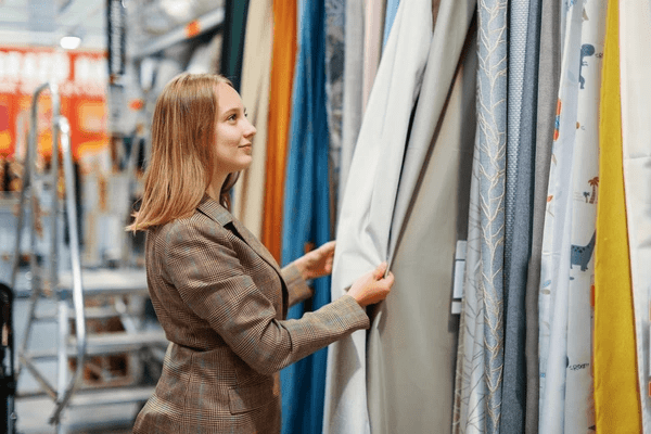 Woman exploring fabric options at a top-rated Emirati curtains and blinds shop in Dubai 2025.