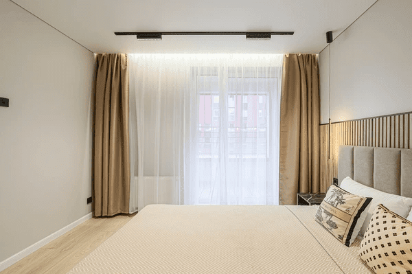 Stylish bedroom with modern ceiling-mounted track curtains in beige and white, creating a soft, cozy, and elegant ambiance.