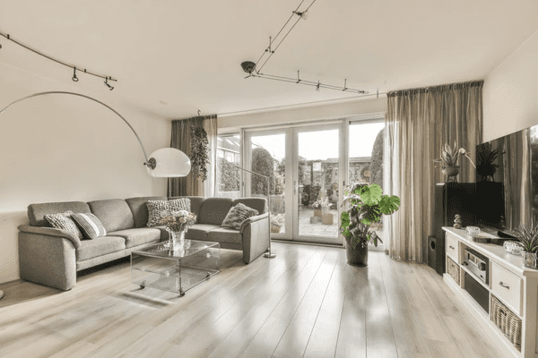 Modern living room with floor-to-ceiling track curtains, a grey sectional sofa, and bright natural lighting in Dubai.

