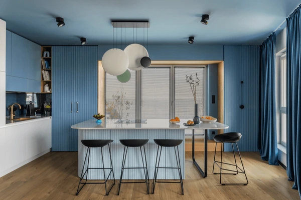 Contemporary Dubai kitchen featuring bold blue curtains, stylish island seating, and minimalist pendant lighting in a trendy, luxurious setting.