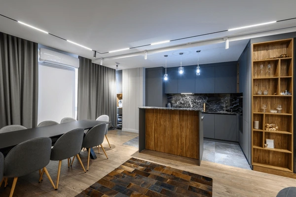 Modern Dubai kitchen and dining space with charcoal grey floor-to-ceiling curtains, wooden accents, and elegant lighting.