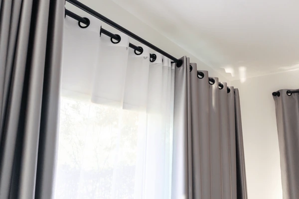 Luxurious grey grommet-style curtains with sheer white drapes, ideal for pink walls in modern Dubai homes.
