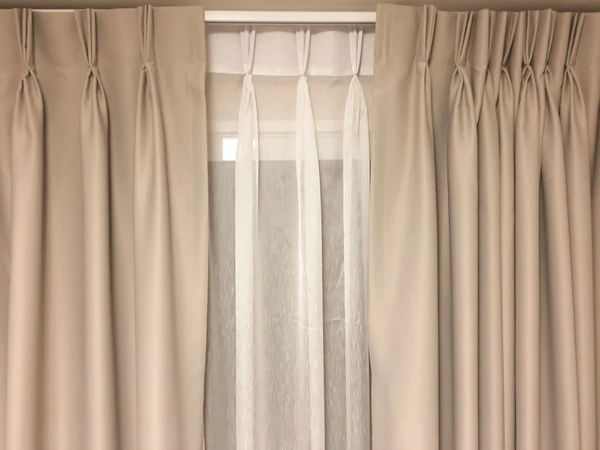 Modern double layered curtains with beige blackout fabric and sheer white inner drapes, offering style and light control.