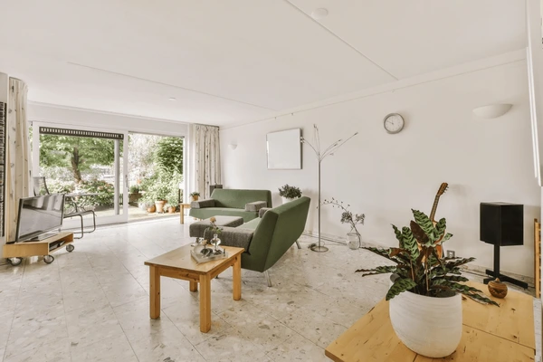 Bright living room with green sofas, wooden furniture, sliding glass doors, and fire-resistant curtains in Dubai 2025.