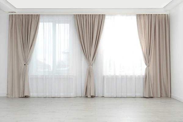 Modern Dubai living room with beige curtains and sheer white drapes on large windows, minimalist and cozy 2025 design.