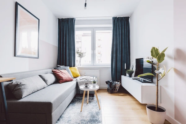 Minimalist Dubai apartment living room with dark teal curtains, gray sofa, and modern décor in 2025.