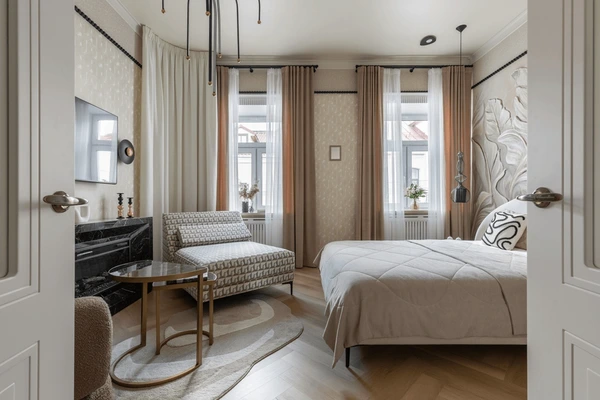 Stylish Dubai bedroom with layered blackout and sheer curtains, neutral-toned bedding, patterned armchair, and modern decor.