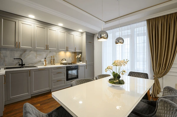 Elegant metallic white and golden curtains in a stylish Dubai kitchen-dining space with grey cabinets, marble backsplash, and modern pendant lights.