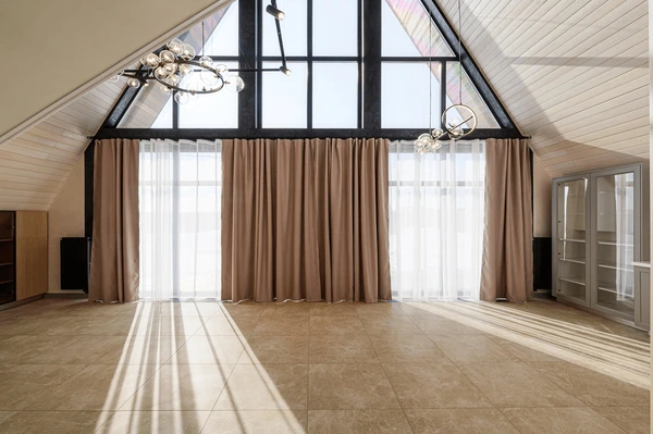 Spacious attic room in Dubai with large triangular windows and beige floor-to-ceiling curtains paired with sheer white drapes.