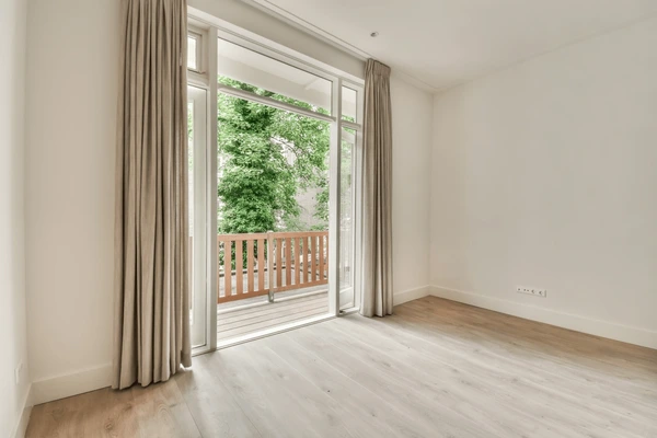 Elegant balcony door with neutral-colored hanging curtains in a minimal modern room with wooden flooring in Dubai 2025.