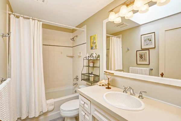 Stylish bathroom with white hanging curtains, vanity mirror, sink, and warm lighting – a cozy and elegant bathroom trend in Dubai 2025.