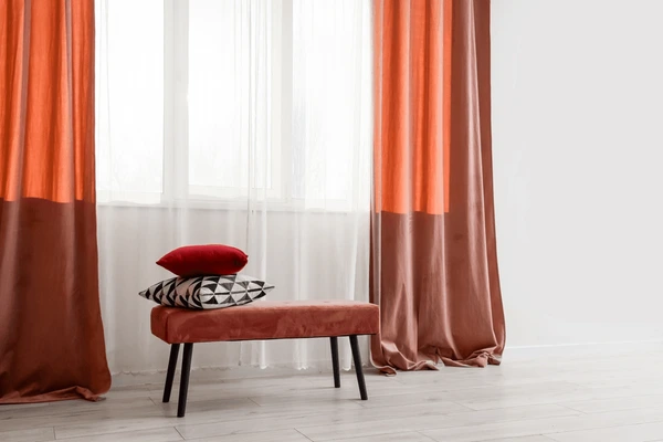 Stylish red and orange falling curtains in Dubai 2025 with a modern bench and cushions, perfect for trendy cozy homes.