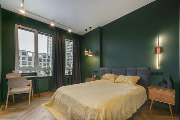 Modern bedroom with deep green walls, dark elegant curtains, and cozy interior design in Dubai 2025.