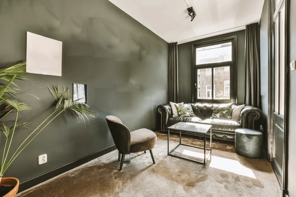 Contemporary living room with deep green wall, elegant dark green wall curtains, leather sofa, and stylish décor in Dubai 2025.