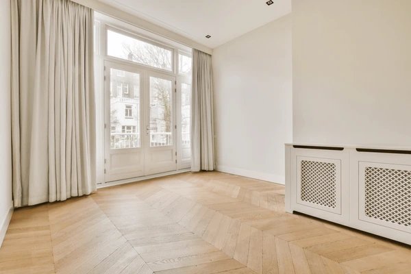 Spacious villa living room in Dubai with full-length cream long curtains, wooden flooring, and large French windows.