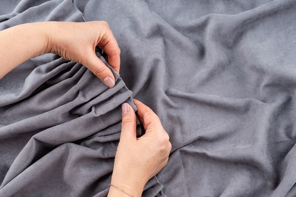 Close-up of a woman’s hands fixing and adjusting elegant gray short curtains, showcasing luxurious fabric and modern design trends in Dubai 2025.