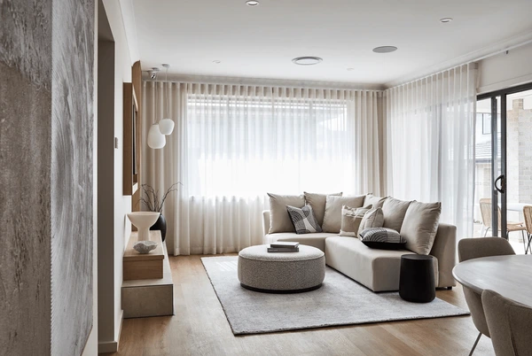 Neutral-toned modern living room with a beige sofa, round coffee table, and normal sized short curtains in Dubai 2025.