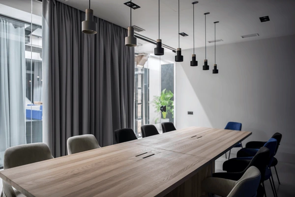Modern office conference room with elegant gray hanging curtains, wooden meeting table, and contemporary pendant lighting in Dubai 2025.