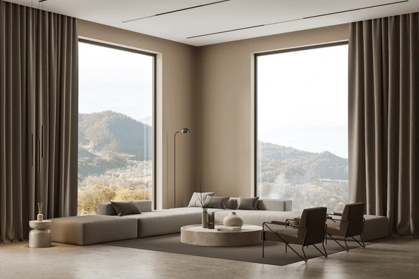 Spacious modern living room with large windows dressed in beige measured curtains, sleek furniture, and scenic mountain view in Dubai 2025.