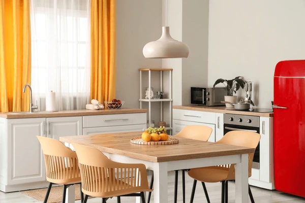 Modern kitchen with bright mustard yellow curtains, wooden dining table, and red retro refrigerator creating a stylish Dubai home interior.
