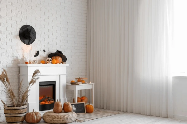Beautiful white Halloween-themed living room in Dubai 2025 with sheer curtains, pumpkins, a white fireplace, and stylish witch decor creating a cozy festive ambiance.
