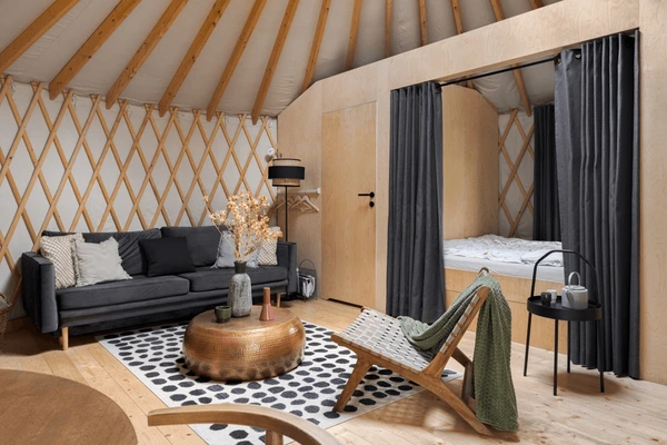 Stylish rustic yurt interior in Dubai with grey traditional curtains, wooden walls, and modern furniture design.