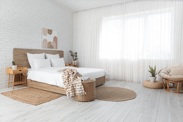 Bright minimalist bedroom in Dubai featuring soft traditional white curtains, a wooden bed, and natural decor for a calm and elegant atmosphere.