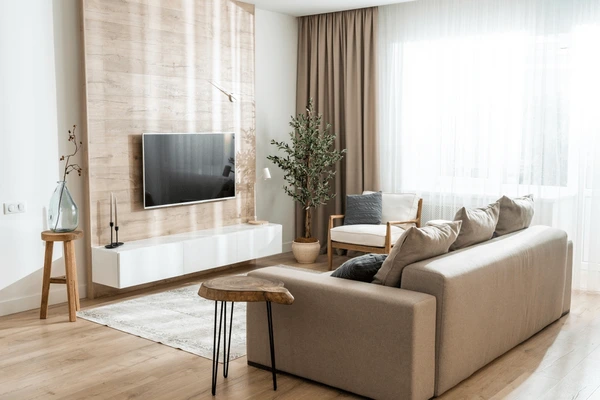 A stylish modern living room in Dubai featuring neutral beige curtains, a sleek sofa, wooden textures, and natural light creating a warm, minimalist November ambiance.